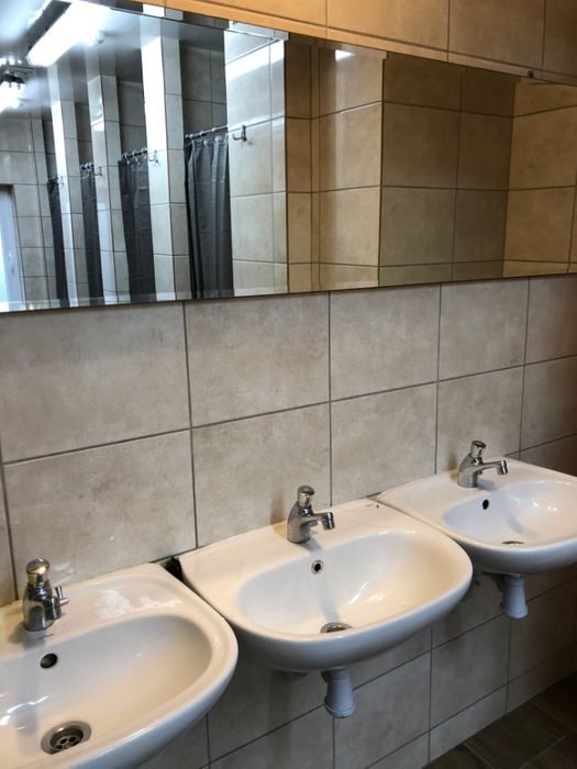 Umywalnia z rzędem umywalek i lustrem
