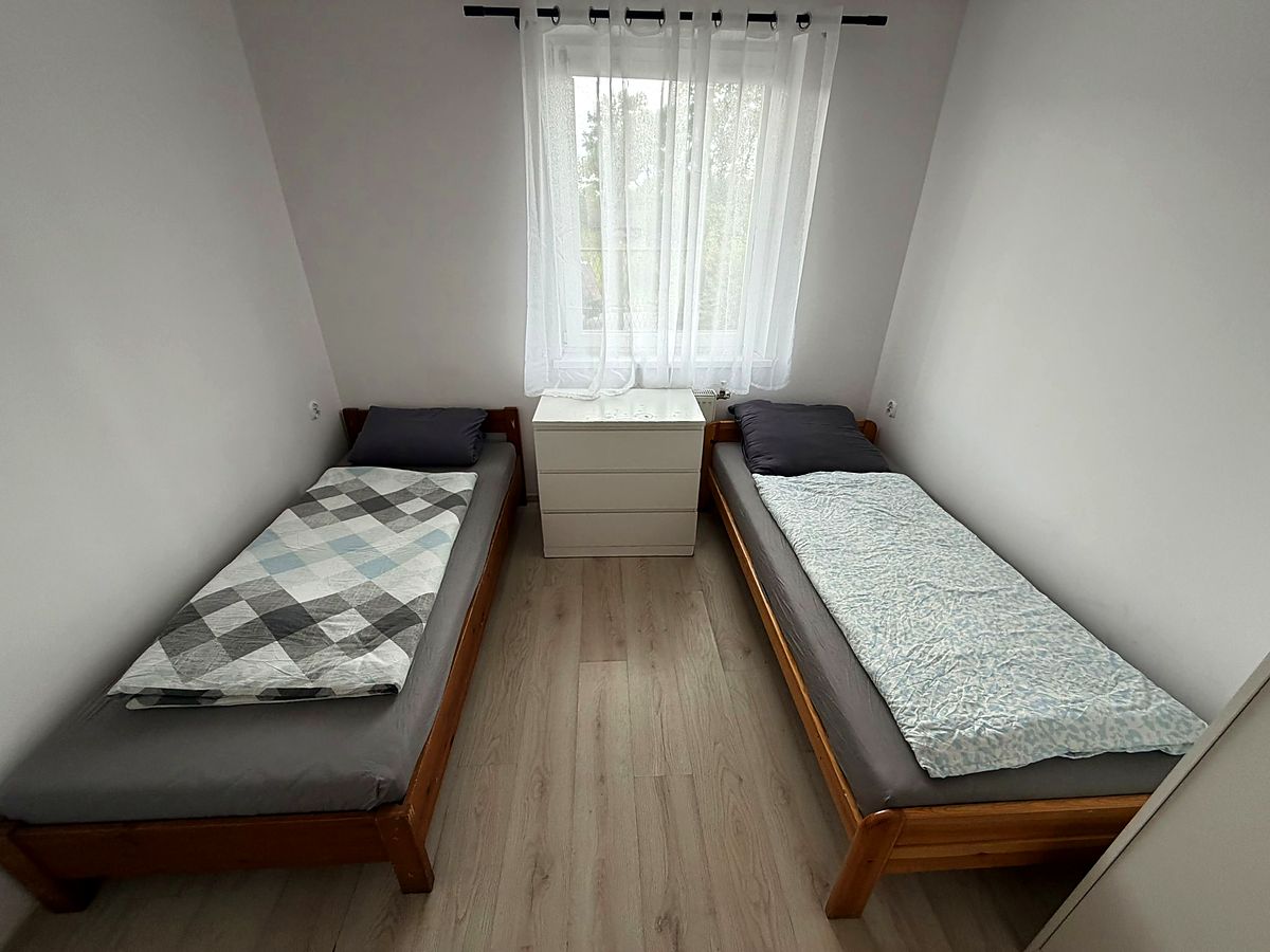 Pokój na poddaszu z dwoma pojedynczymi łóżkami i szafką nocną
